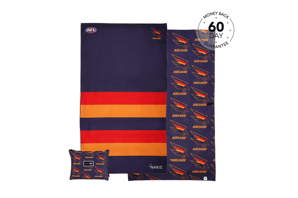 Adelaide Crows AFL beach towel with navy, red and gold horizontal stripes, displayed flat with matching patterned pillow and 