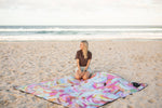 Recycled picnic blanket with multicolored abstract watercolor print, spread on beach sand with woman kneeling on it preview #12