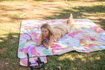 Recycled picnic blanket with multicolour abstract watercolour print, displayed on grass with carrying straps visible. preview #13
