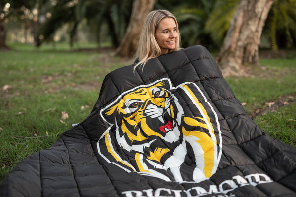 Black quilted puffy blanket with yellow and white tiger head graphic and Richmond Tigers stripes, draped outdoors.