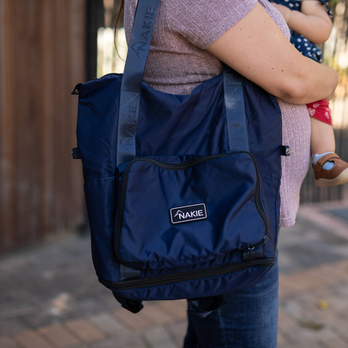 Navy recycled tote bag with dual handles and front pocket, worn over shoulder on person