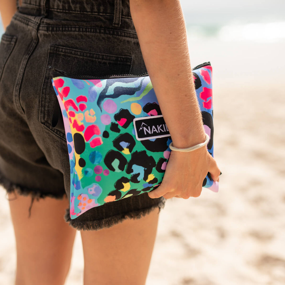 Multicoloured sand-free beach towel with leopard print and floral pattern, held at beach