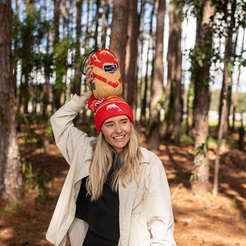 Woman in beanie holding NRL Nakie Dolphins Hammock packed in its stuff sack